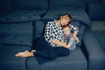 Wall Mural - Beautiful woman with child. Woman in a shirt. Family sitting on the couch.