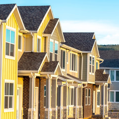 Square frame Townhouses with gable roof and stairs at the entrance framed by square columns