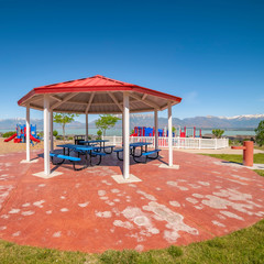 Wall Mural - Square frame Octagon shaped picnic pavilion with view of colorful playground and scenic lake