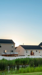 Wall Mural - Vertical Facade of houses in the suburb with view of green grassy terrain and shiny pond