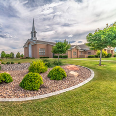 Wall Mural - Square Scenic view of church with white steeple and landscaped yard on a cloudy day