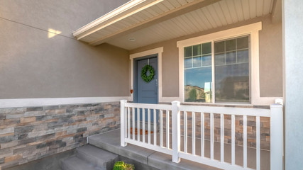 Wall Mural - Pano Home facade with small porch and blue gray front door with green leafy wreath