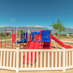 Wall Mural - Square frame Fun colorful childrens playground overlooking lake snowy mountain and blue sky