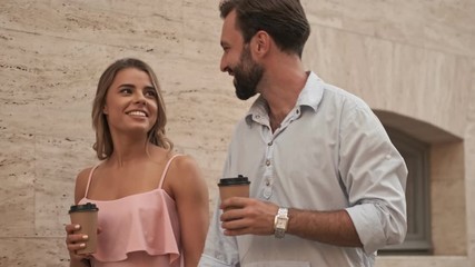 Poster - Cheery happy young loving couple are walking by street outdoors looking at each other