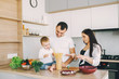 © hetmanstock2 - Family in a kitchen. Beautiful mother with little son. Father in a white t-shirt.