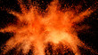 Explosion of orange powder isolated on black background