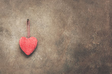 A Red Heart Is Hanging On A Dark Brown Rustic Wall. Valentine's Day. Copy Space. Toned.