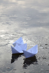 Wall Mural - three paper boats sail on frozen water