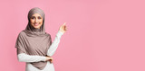 Fototapeta  - Smiling arabian girl pointing at copy space over pink background