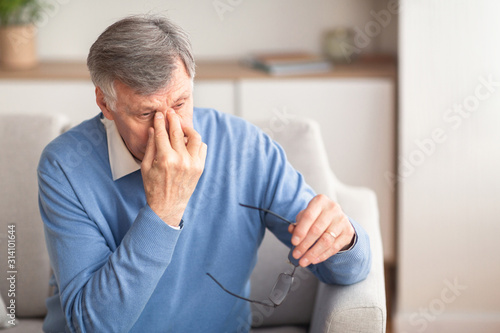 Cuadros en Lienzo Senior Man Massaging Nosebridge Sitting On Sofa, Selective Focus