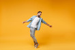 © ViDi Studio - Laughing young bearded man in casual blue shirt posing isolated on yellow orange background studio portrait. People emotions lifestyle concept. Mock up copy space. Standing on toes, spreading hands.