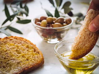 dipping piece of bread on extra virgin oil bowl. bread and olives near. Healthy food, healthy diet, traditional mediterranean product 2