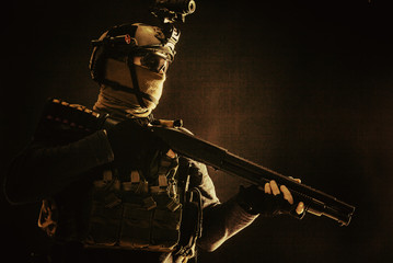 Shoulder portrait of army elite troops soldier, anti-terrorist tactical team wit shotgun, helmet with thermal imager, hiding face behind mask, armed rifle with optical scope, studio shoot on black