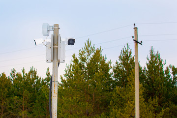 Two surveillance cams on top of a pole, seen from below against a blue sky