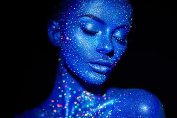 Fashion model woman in blue bright sparkles and neon lights posing in studio.  Portrait of beautiful sexy woman. Art design colorful glitter glowing make up