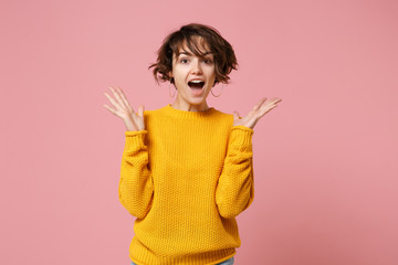 Wall Mural - Excited young brunette woman girl in yellow sweater posing isolated on pastel pink wall background, studio portrait. People lifestyle concept. Mock up copy space. Keeping mouth open, spreading hands.