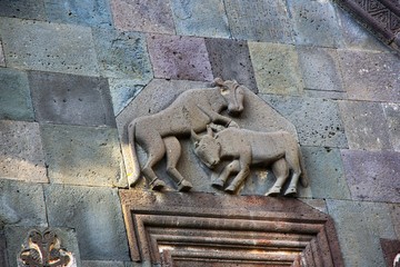 Three dimensional bas relief of battle of lion and bull on facade of main temple of medieval monastery complex Geghard.