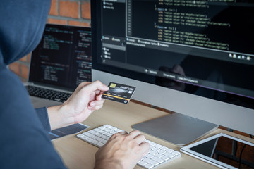 Wall Mural - computer hacker or cyber attack concept, dangerous hooded hacker using multiple computers typing bad