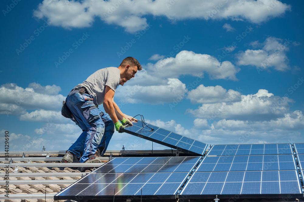Installing solar photovoltaic panel system. Solar panel technician installing solar panels on roof. Alternative energy ecological concept. - obrazy, fototapety, plakaty 