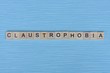 © butus - gray word claustrophobia from small wooden letters on a blue table