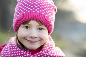 Wall Mural - Pretty child girl in warm knitted winter clothes outdoors.