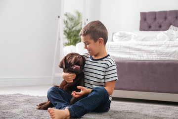 Wall Mural - Little boy with puppy on floor in bedroom. Friendly dog