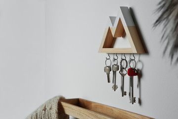 Wooden key holder on light wall indoors. Space for text