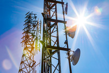 Bright Sun Shine Over Two Cell Site Towers, Radio And GPS Transmitter And Receiver, Associated With Electromagnetic Pollution, With Vibrant Lens Flare