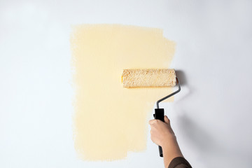 Sticker - Woman painting white wall with beige dye, closeup