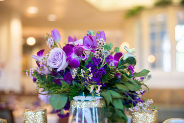 Purple rose and flowers bouquet table centerpiece on wedding reception sweetheart table.