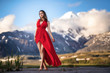 © filin174 - girl in a long red dress on a background of majestic mountains.