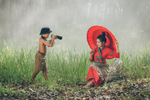 Asia Children Taking A Picture For A Beautiful Woman At Countryside,Rural Concept,Boy Takes Pictures Of His Girl Outdoors.