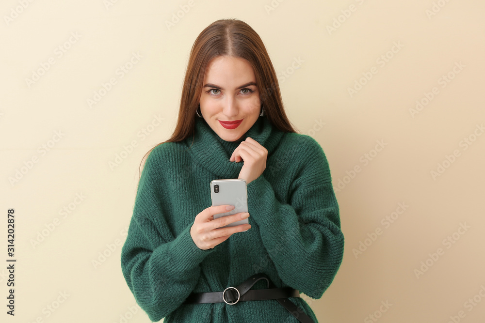 Beautiful young woman with mobile phone on light background