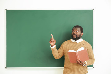 Wall Mural - African-American teacher near blackboard in classroom