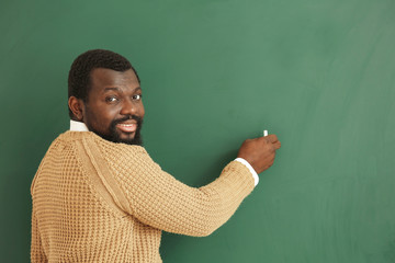 Wall Mural - African-American teacher writing on blackboard in classroom