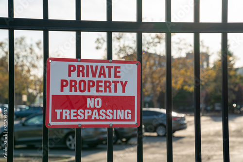 Fotografía Private property no trespassing sign on black gate in front of parking lot