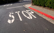 Stop sign painted on asphalt of red curb street at intersection