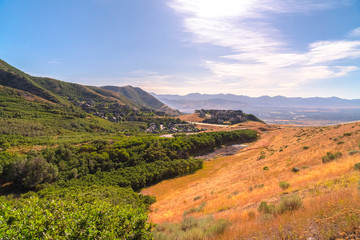 Wall Mural - Scenic mountain landscape with houses amidst vast slopes covered with greenery