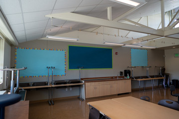 Empty classroom with blank decorations and tables and chairs stacked during summer