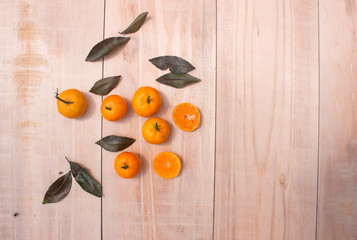 Wall Mural - Fresh mandarin oranges fruit or tangerines with leaves on wooden table, copy space