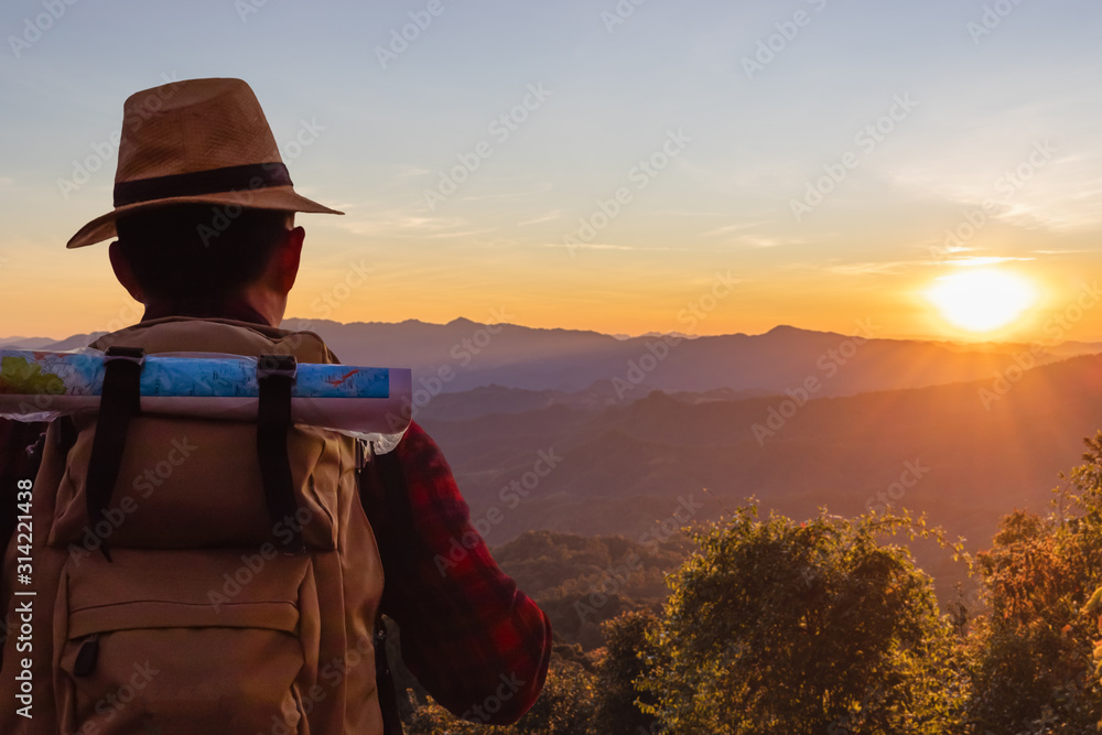 male tourist with backpacks stand to the top of mountain and enjoying sunset. - obrazy, fototapety, plakaty 