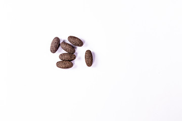 Ayurvedic medicine concept. simplistic photo of brown herbal pills scattered on white background