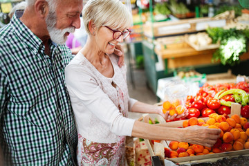 Wall Mural - Senior family couple choosing bio food fruit and vegetable on the market during weekly shopping