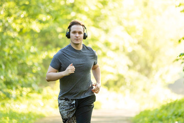 young man runs in a forest and makes fitness