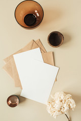 Wall Mural - Blank paper sheets with empty copy space for text, envelopes, hydrangea flower on beige background. Flat lay, top view invitation concept.