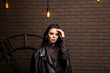 © Сергей Луговский - brunette in a black leather jacket on a background of a brown brick wall and a clock