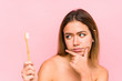 Young caucasian woman holding a teeth brush isolated looking sideways with doubtful and skeptical expression.