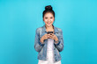 Portrait of Happy asian woman feeling happiness and looking camera holding smartphone on blue background. Cute asia girl smiling wearing casual jeans shirt and connect internet shopping online