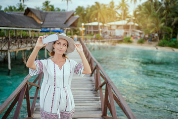 Wall Mural - Vacation and technology. Outdoor portrait of pretty young woman taking selfie with her  smartphone on tropical beach.