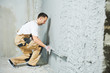 © Kadmy - Plasterer using screeder smoothing putty plaster mortar on wall